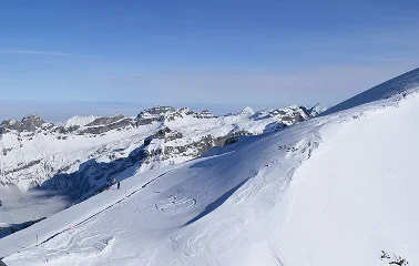 Snow-covered ski slopes and mountain peaks at Jackson Hole resort under clear blue winter sky