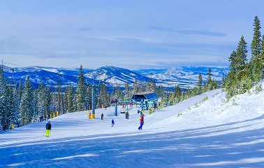 Pristine ski slopes at Vail with skiers descending powdery runs surrounded by snow-covered mountains