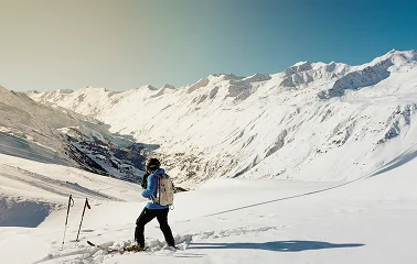 Skier descending pristine powder slopes surrounded by snow-covered mountain peaks in alpine terrain